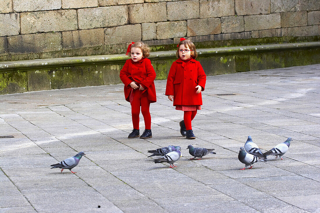 Two children playing with pigeons, Praza da Quintana, Santiago de Compostela, Galicia, Spain