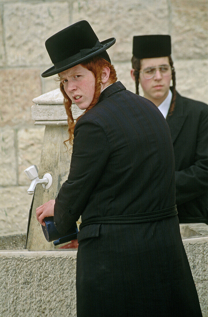 Young orthodox Jews washing their hands in a fountain. Jerusalem