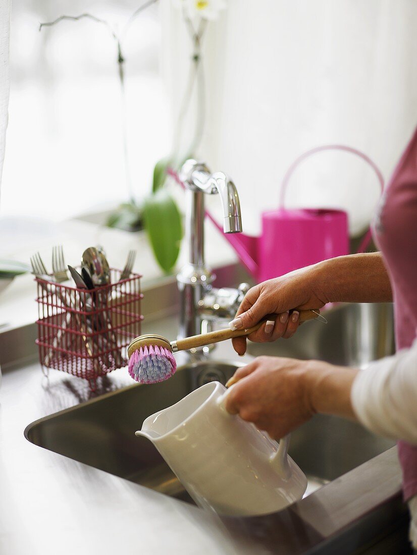 A woman rinsing a white porcelain jug