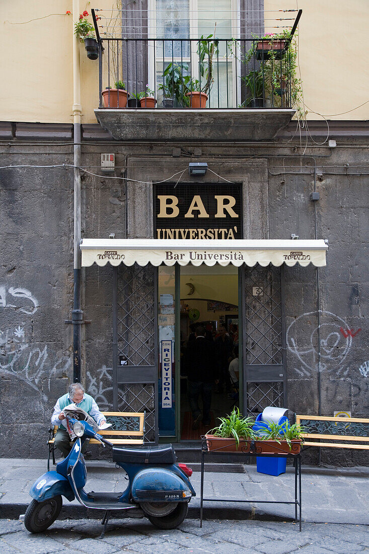 Mann sitzt auf Bank vor Bar Universita in der Altstadt von Neapel, Kampanien, Italien, Europa