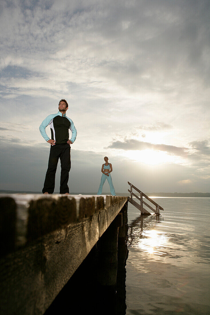 Couple standing on jetty at Lake Starnberger, Muensing, Bavaria, Germany, MR
