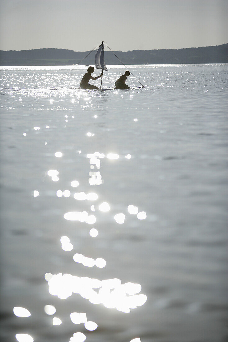Two kids on a small raft with sail, Ammerland, Lake Starnberg, Bavaria, Germany