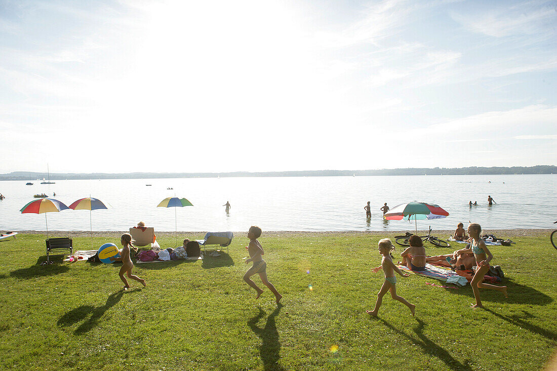 People sunbathing and children playing on the lake shore, Buchscharn, Lake Starnberg, Bavaria, Germany