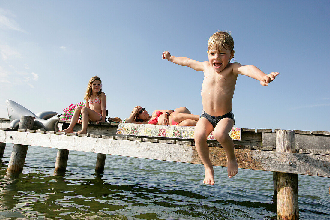 Junge springt vom Steg ins Wasser, Karniffelbach, Starnberger See, Münsing, Bayern, Deutschland, MR