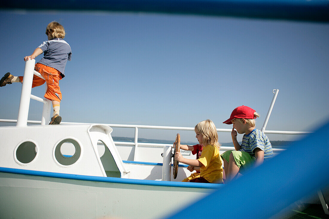 Children playing in a boat on a playground, Lake Starnberg, Bavaria, Germany