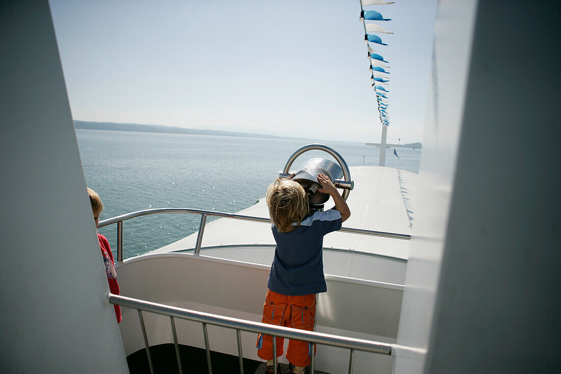 Boy looking through binoculars on a boat, Lake Starnberg, Bavaria, Germany, MR