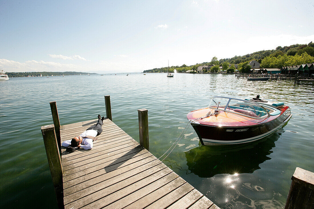 Geschäftsmann entspannt sich am Holzsteg, Starnberg, Starnberger See, Bayern, Deutschland