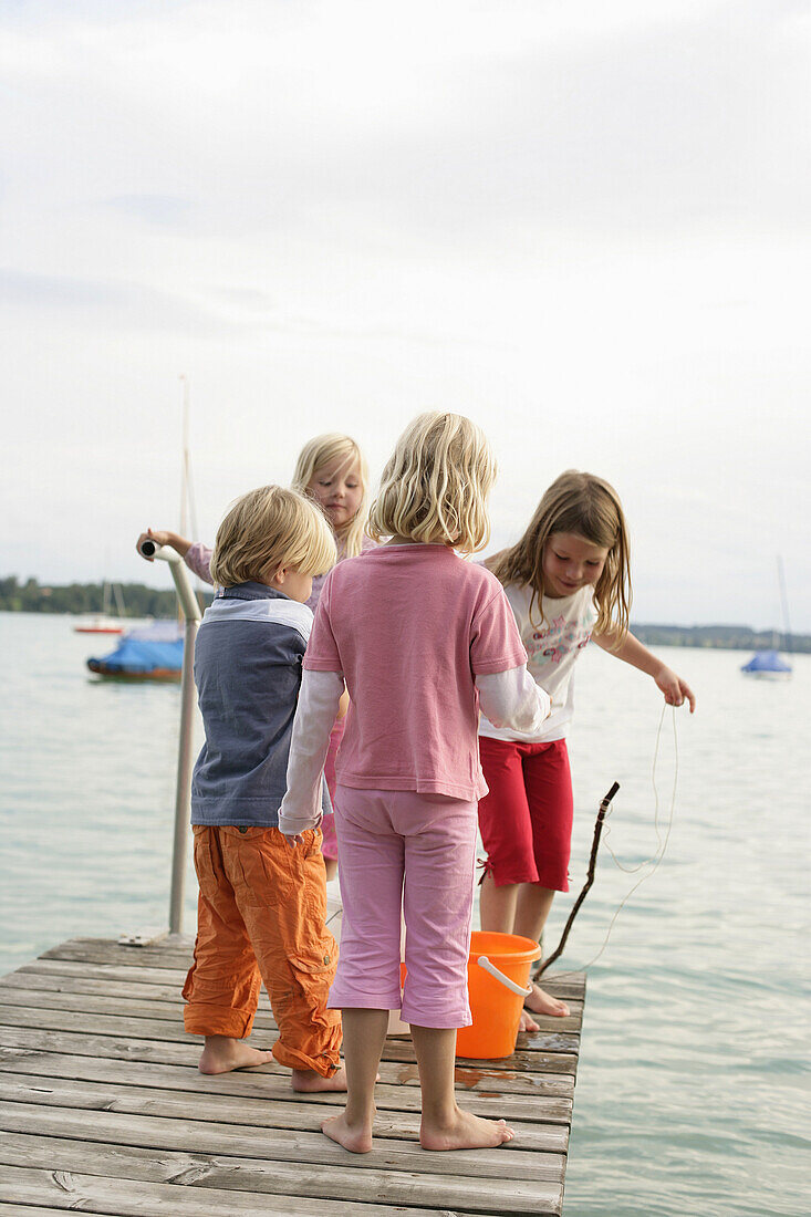 Kinder spielen auf einem Holzsteg am Wörthsee, Bayern, Deutschland, MR