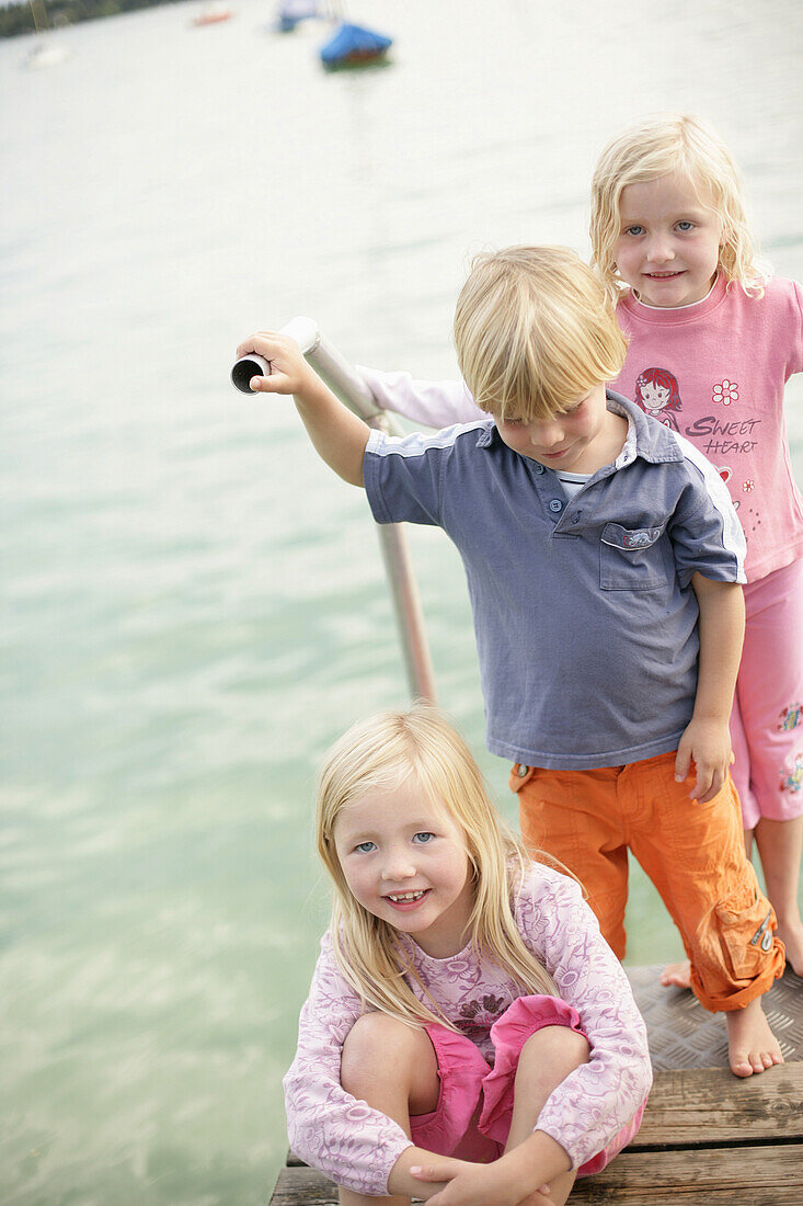 Three children on a jetty at Lake Woerthsee, Bavaria, Germany, MR