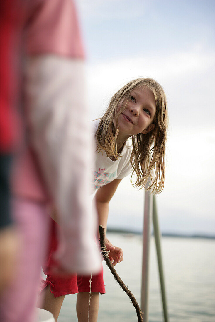 Mädchen mit einer selbstgebauten Angel auf einem Steg am Wörthsee, Bayern, Deutschland, MR