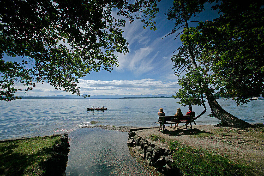 Three people sitting on the lakeshore, kanu in the background, Tutzing, Lake Starnberg, Bavaria, Germany
