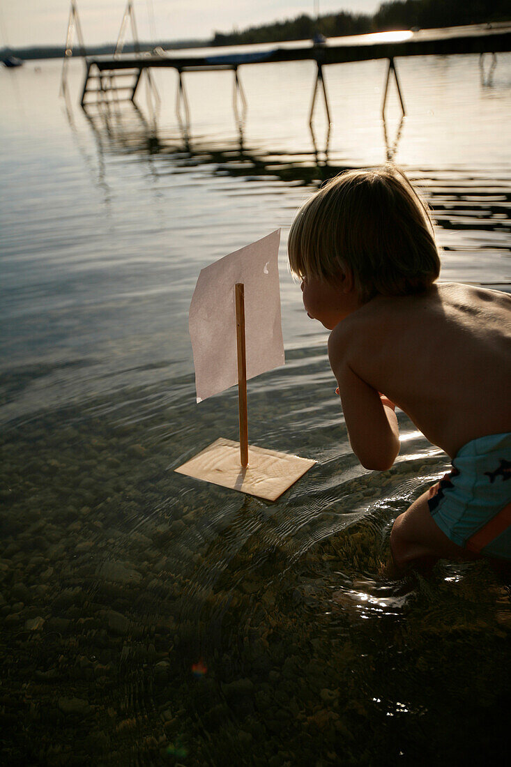 Boy playing with toy float in Lake Wörthsee, Bavaria, Germany, MR