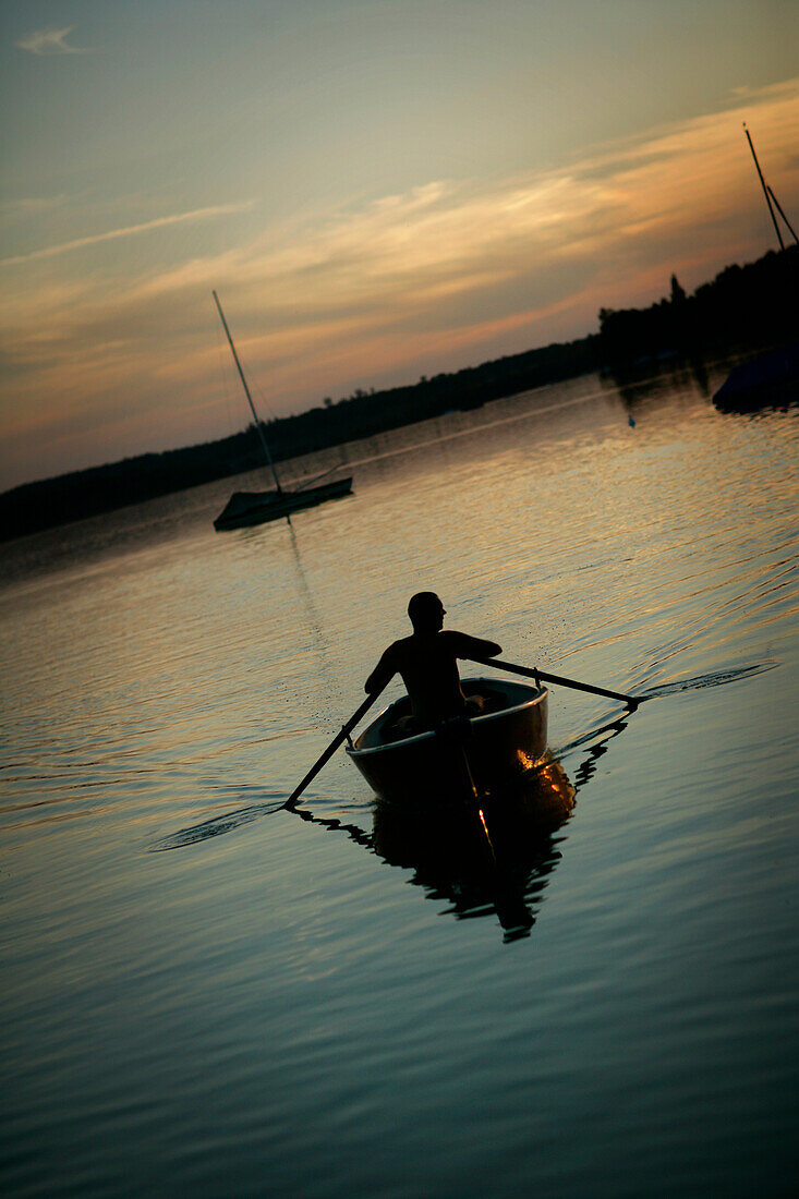 Mann rudert in der Dämmerung auf dem Wörthsee, Bayern, Deutschland, MR