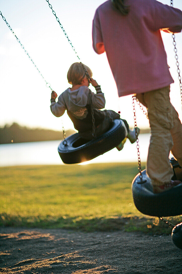 Two children on a swing near the lakeshore, Madkroken, Smaland, Sweden