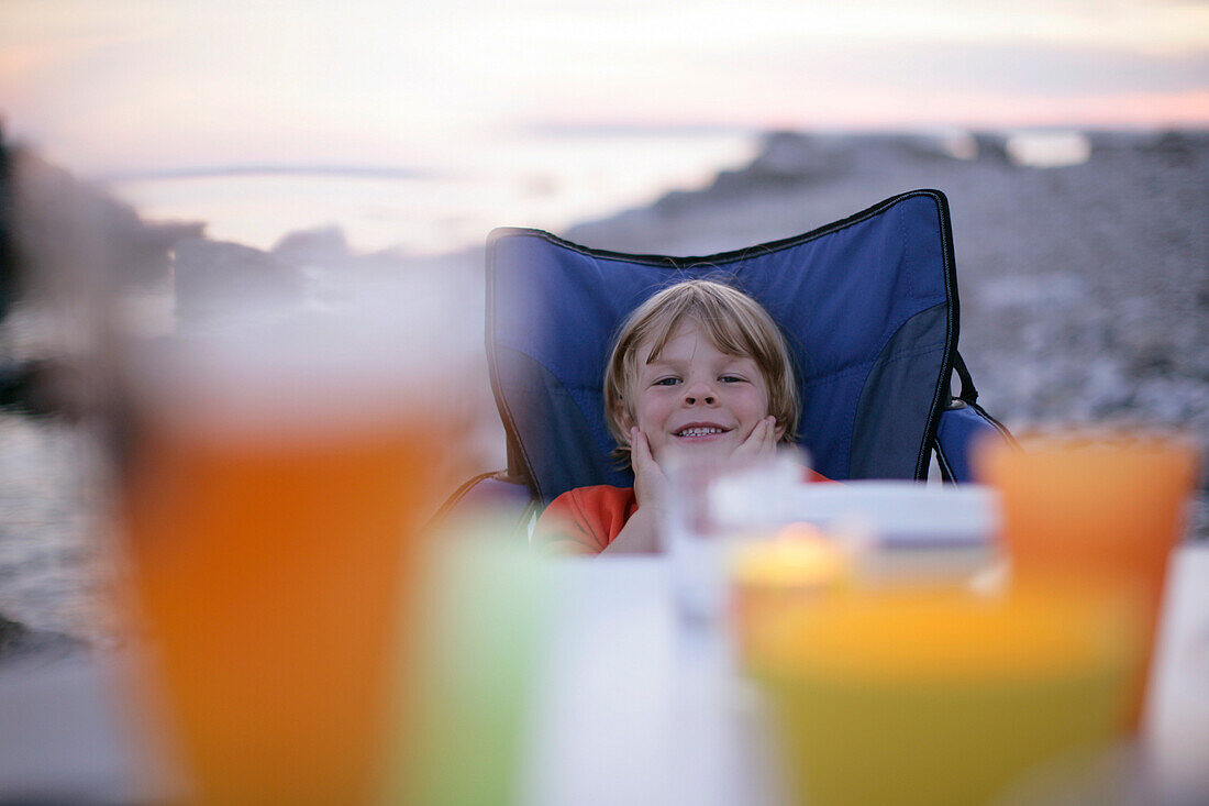 Boy sitting at the table, smiling, by the sea, Sysne, Gotland, Sweden