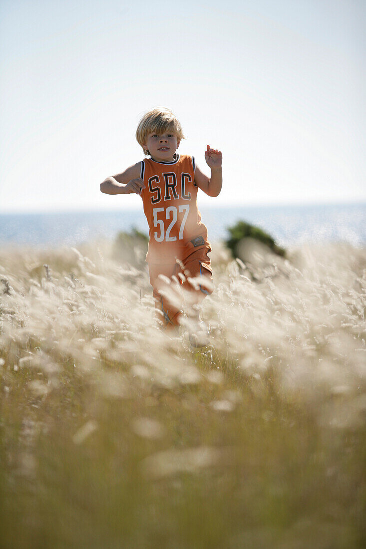 Junge läuft durch Wiese, Strandgrass, Sysne, Gotland, Schweden