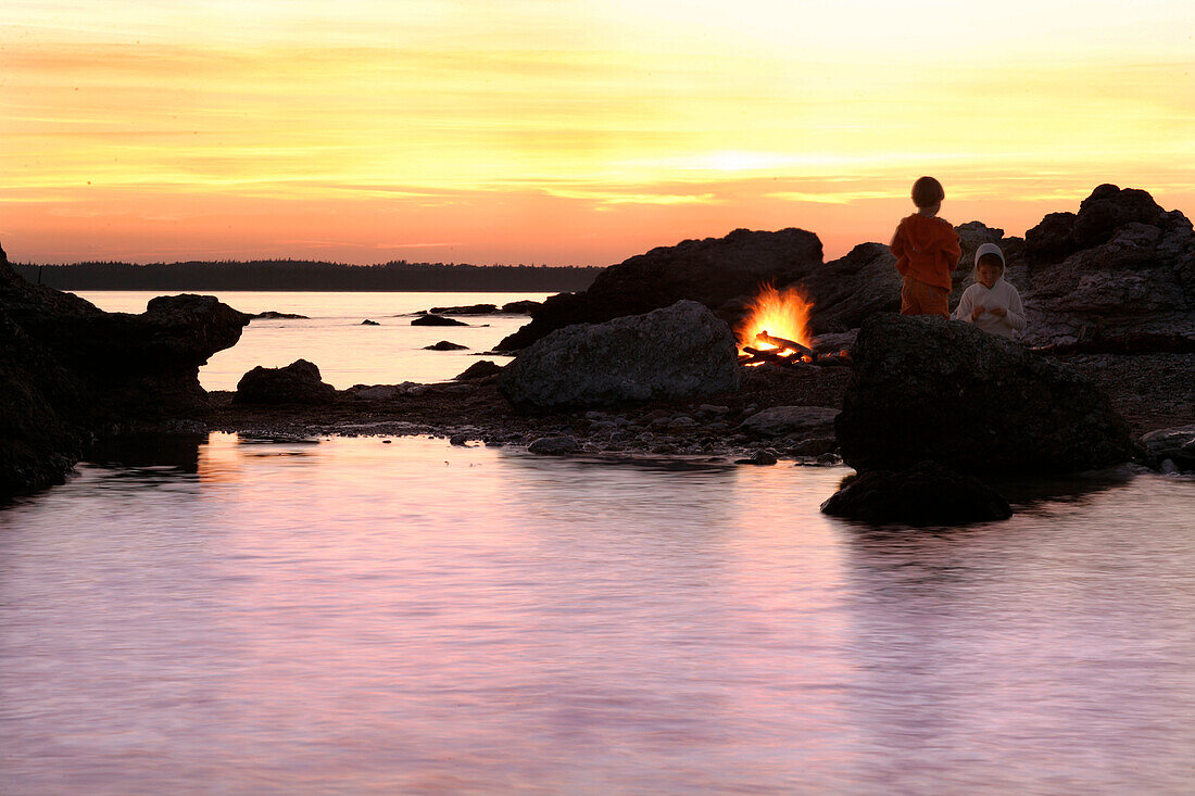 Zwei Kinder beim Lagerfeuer am Strand, Sonnenuntergang, Sysne, Gotland, Schweden