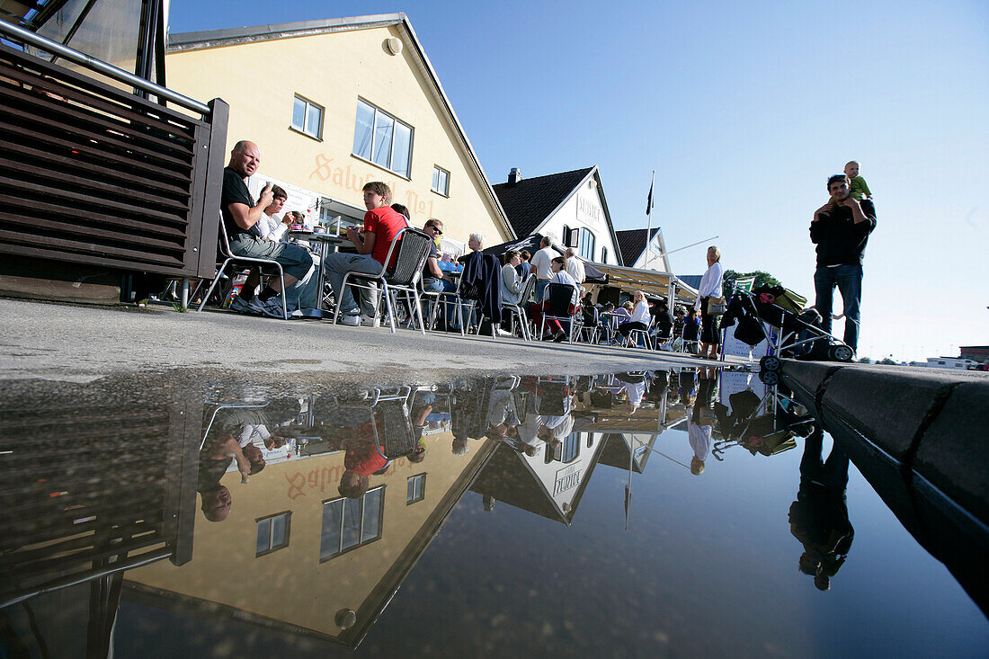 Cafes, quayside promenade, with reflection in a puddle, Visby, Gotland, Sweden