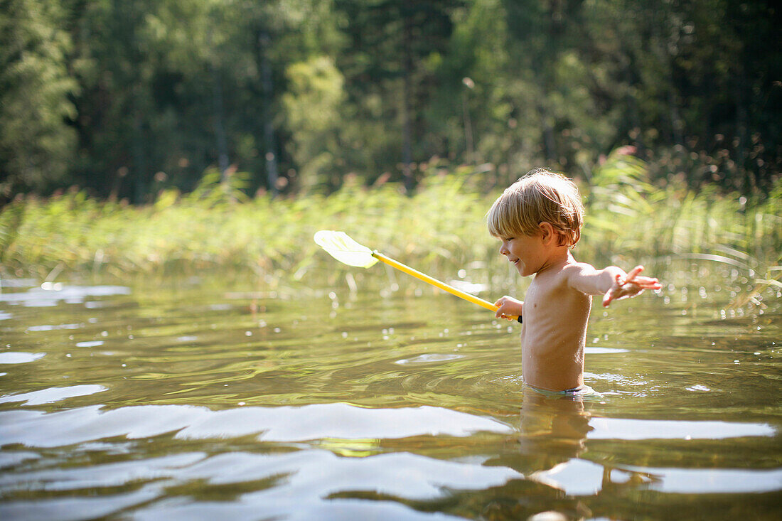 Boy (3-4 years) with a dip net standing in Lake Staffelsee, Upper Bavaria, Bavaria, Germany, MR