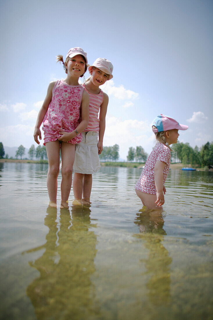 Three girls (3-8 years) standing in water, Lake Staffelsee, Upper Bavaria, Germany