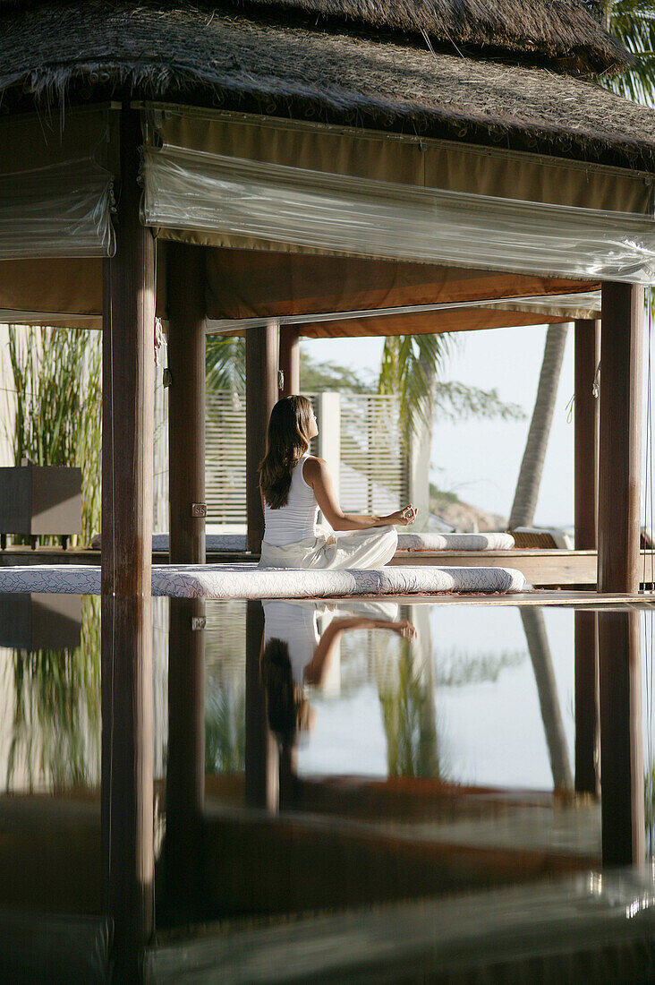 Frau beim Meditieren, Spiegelung im Wasser, Entspannung, Wellness, Urlaub