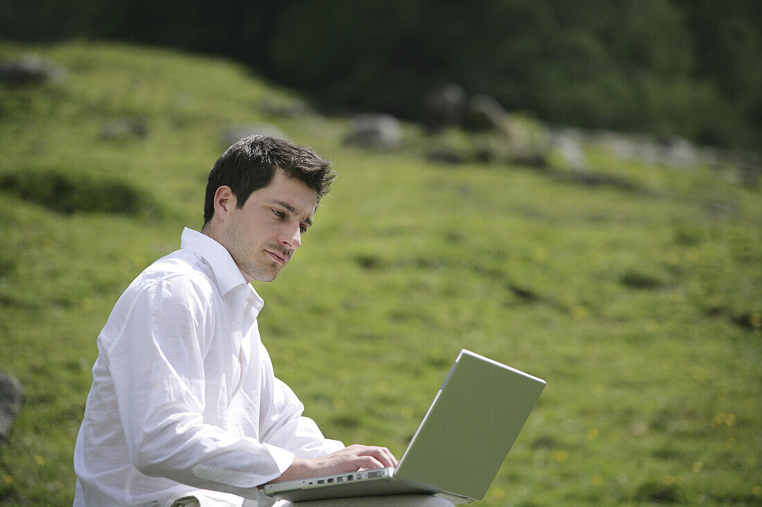 Mann mittleren Alters arbeitet an einem Laptop, Heiligenblut, Hohe Tauern Nationalpark, Kärnten, Österreich