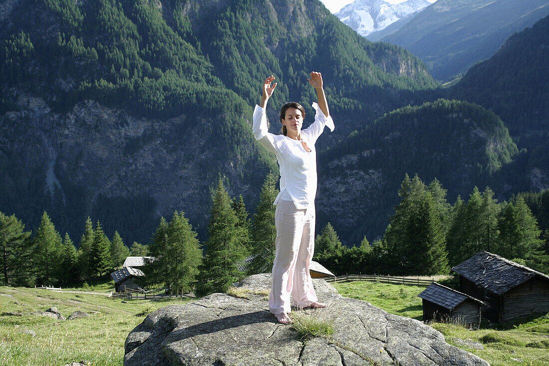 Woman practising yoga on a rock, Heiligenblut, Hohe Tauern National Park, Carinthia, Austria