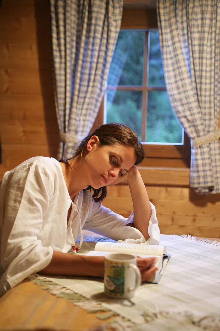 Frau liest ein Buch in einer Almhütte, Heiligenblut, Nationalpark Hohe Tauern, Kärnten, Österreich