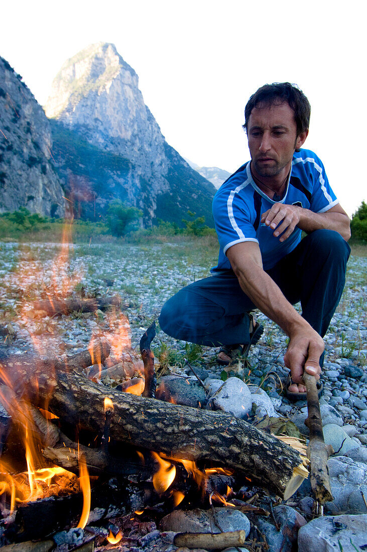 Mann am Lagerfeuer, Berg im Hintergrund, Piccolo Diem, Sarcatal, Trentino, Italien
