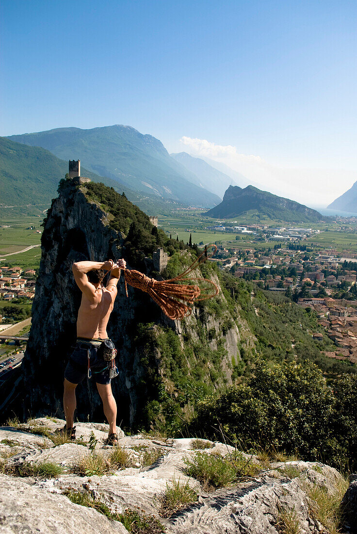 Kletterer auf Gipfel wirft ein Seil, Arco, Trentino-Südtirol, Italien