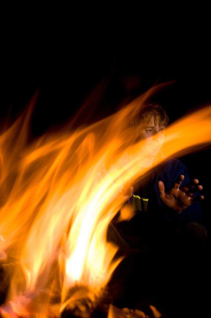 Mann wärmt sich am Lagerfeuer