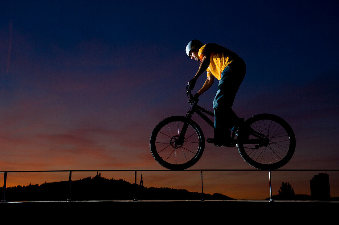 Man trial biking on a balustrade in sunset, Linz, Upper Austria, Austria