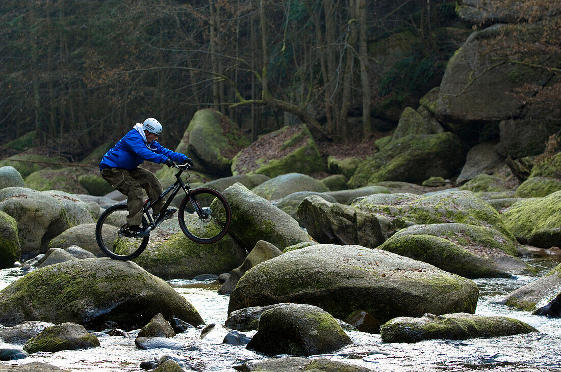 Trial biker on rocks of river, Muelviertel, Austria
