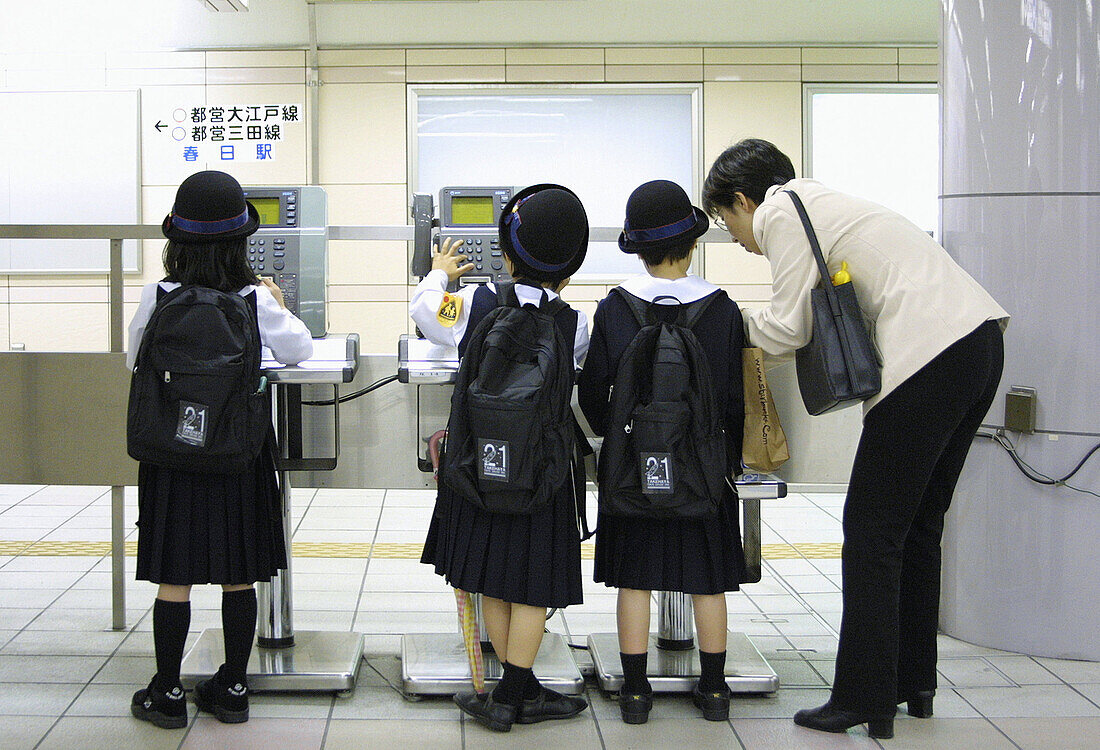 Some school girls are learning how to use a public telephone in the subways of Tokyo. Japan 