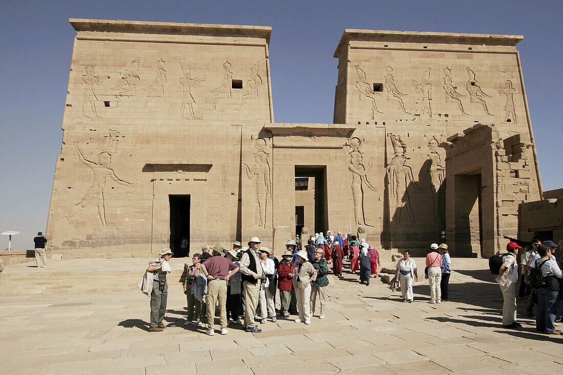 Tourists visiting Philae temple, built for Isis. On the first pylon are pictures of Isis and Horus. Aswan. Egypt