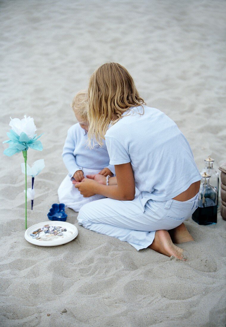 Mädchen spielt mit kleinem Kind im Sand