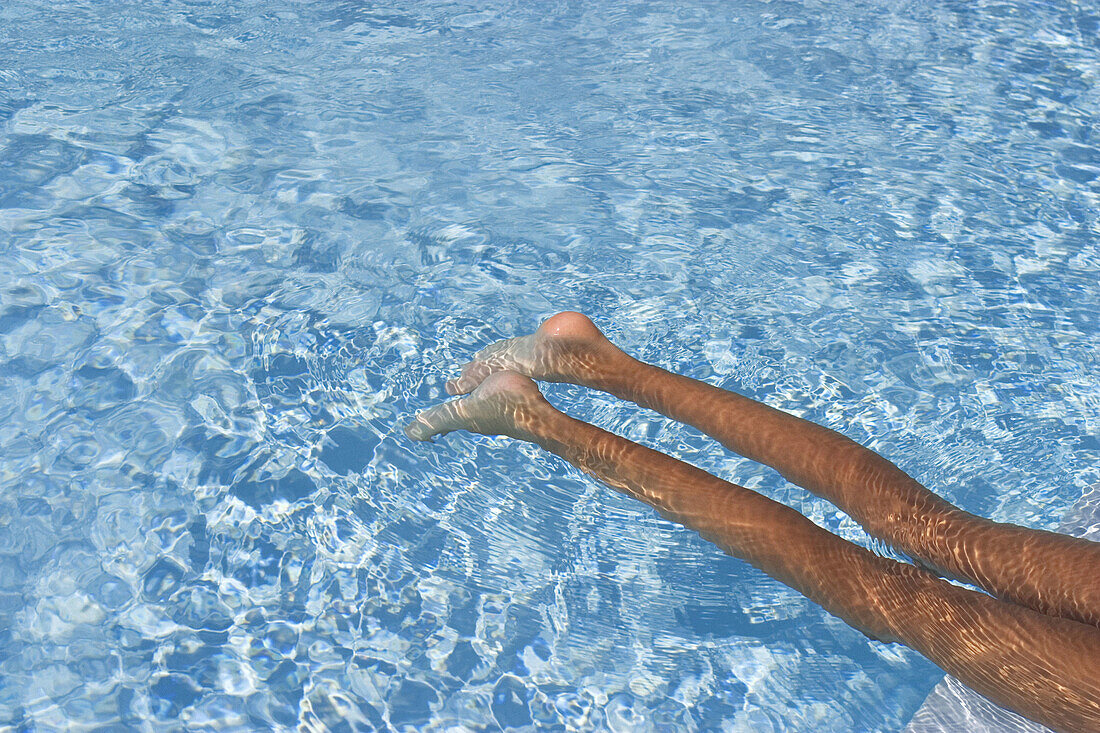 Legs of girl floating in swimming pool
