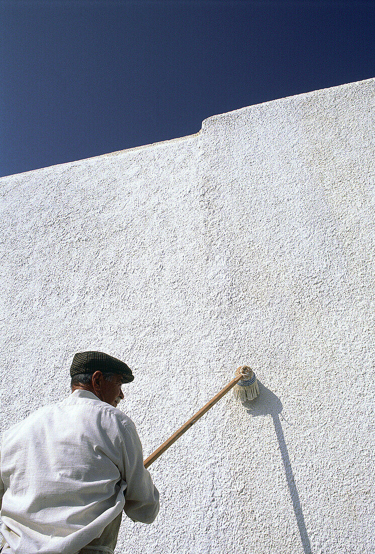 Man painting walls of his house in white. Naxos island. Greece