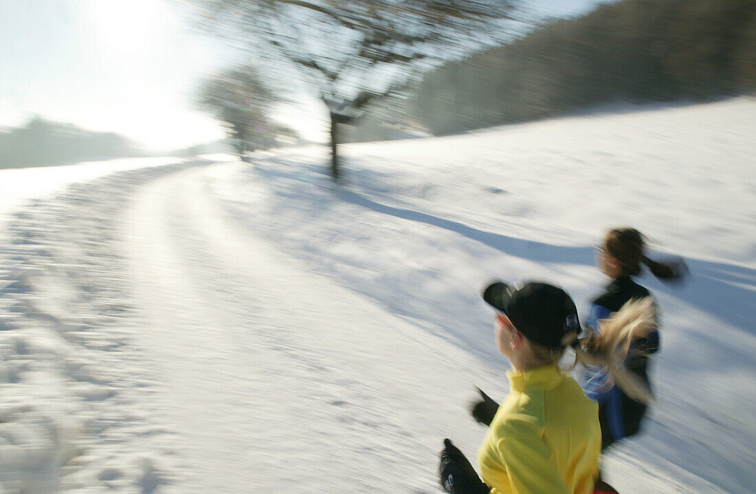 Zwei Frauen joggen über verschneiten Weg, Steiermark, Österreich
