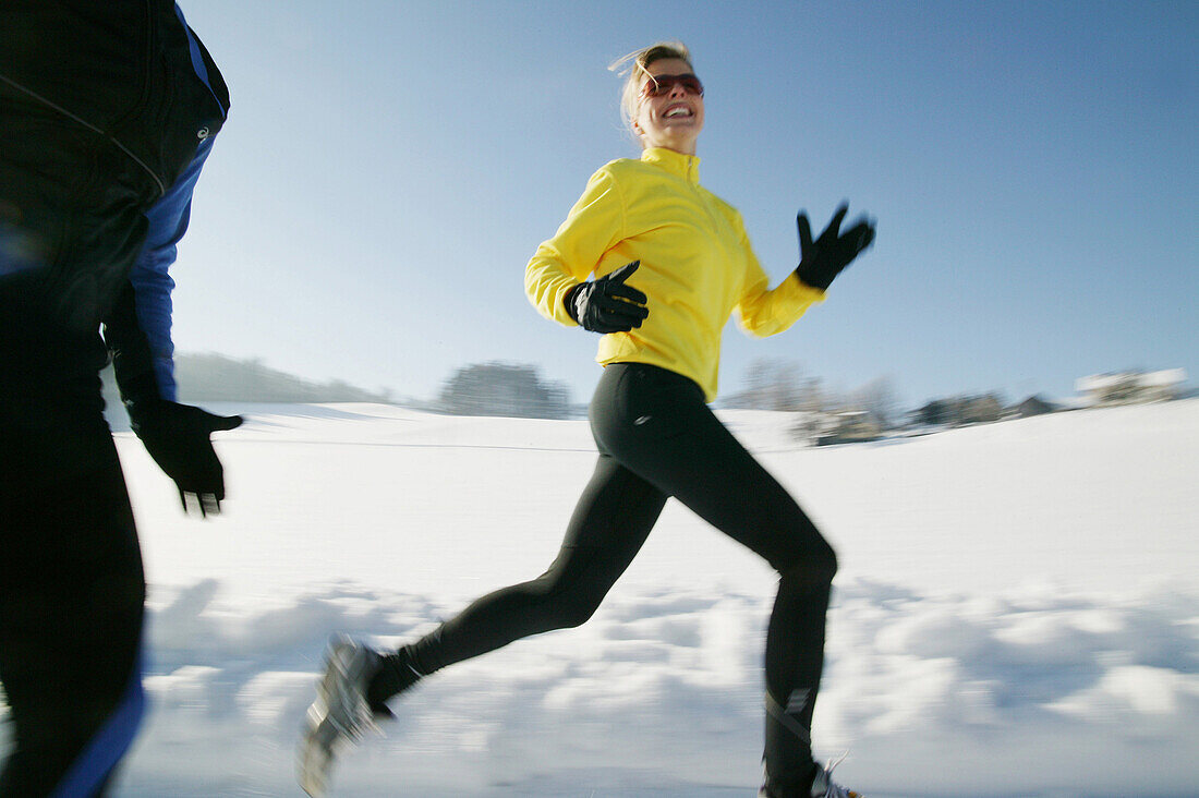 Zwei Frauen joggen über verschneiten Weg, Steiermark, Österreich