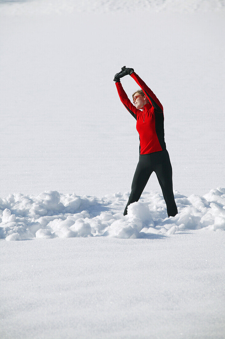Woman stretching in snow, Styria, Austria