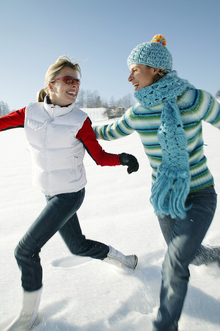 Two women running in snow, Styria, Austria