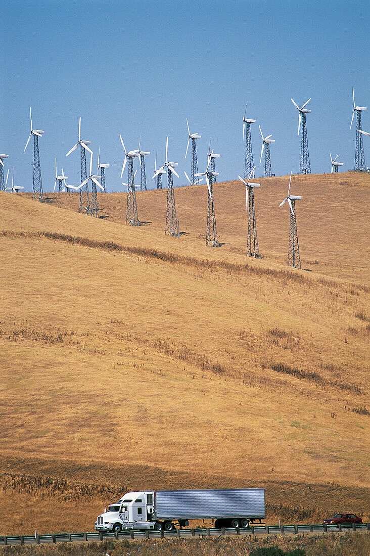 Truck on highway,wind turbines at rear. California. USA