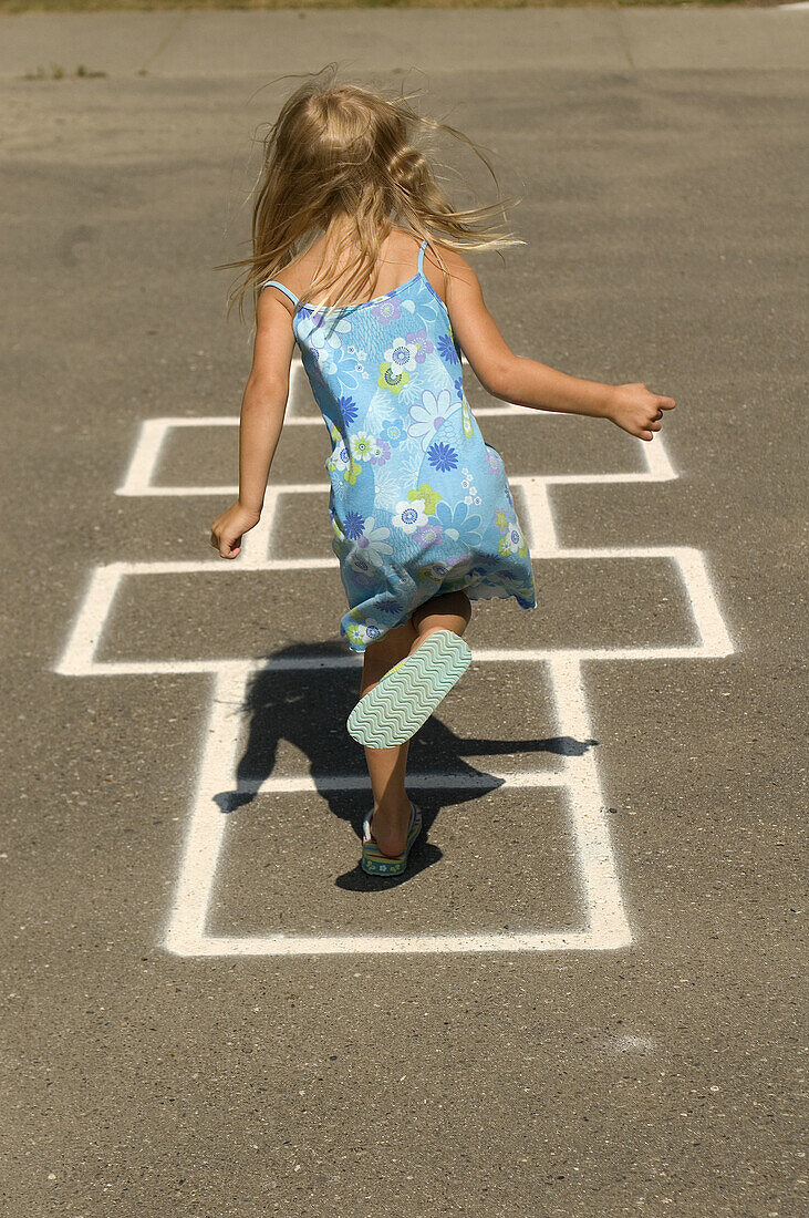 Young girl, 4 years old, playing hopscotch in park. White Rock, BC, Canada. Near Vancouver