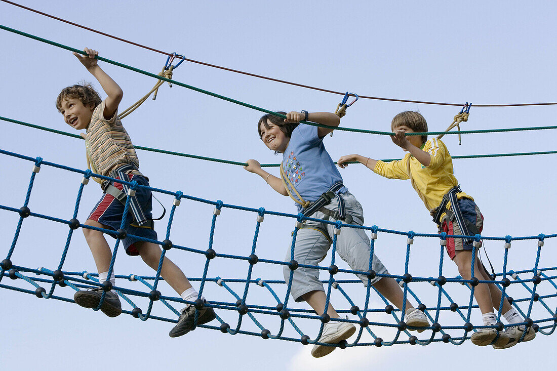 Boys crossing rope bridge in camp