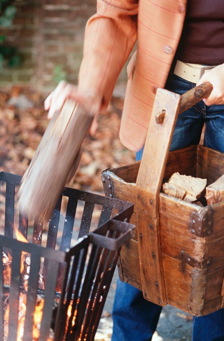 Mann legt Brennholz in das Feuer