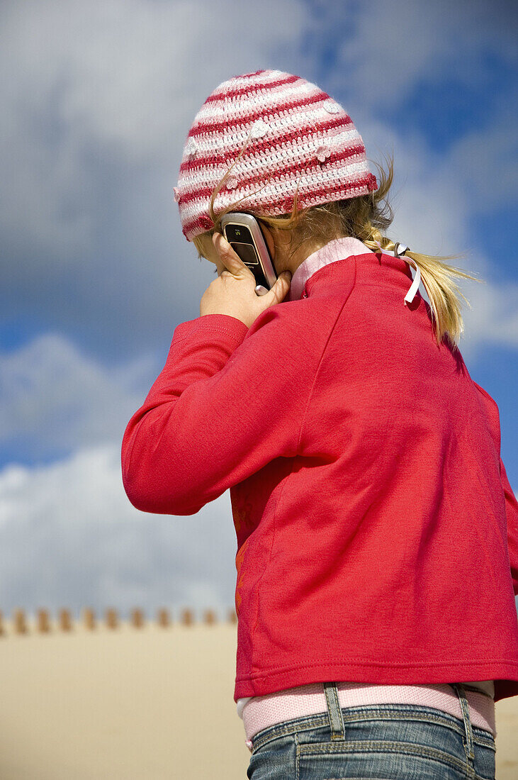 ns, Cell phone, Cell phones, Cellular phone, Cellular phones, Child, Children, Color, Colour, Communication, Communications, Contemporary, Daytime, Exterior, Fair-haired, Female, Girl, Girls, Headgear