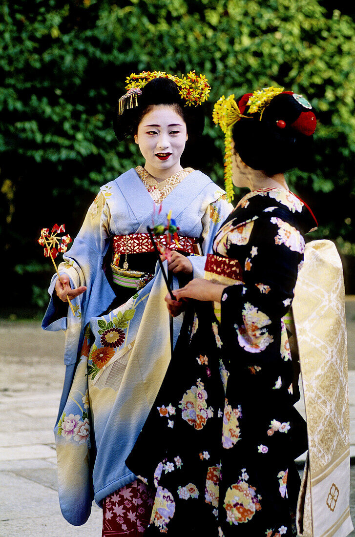Two maikos (geisha apprentice) chating in Kitano Jinja park, Kyoto. Japan