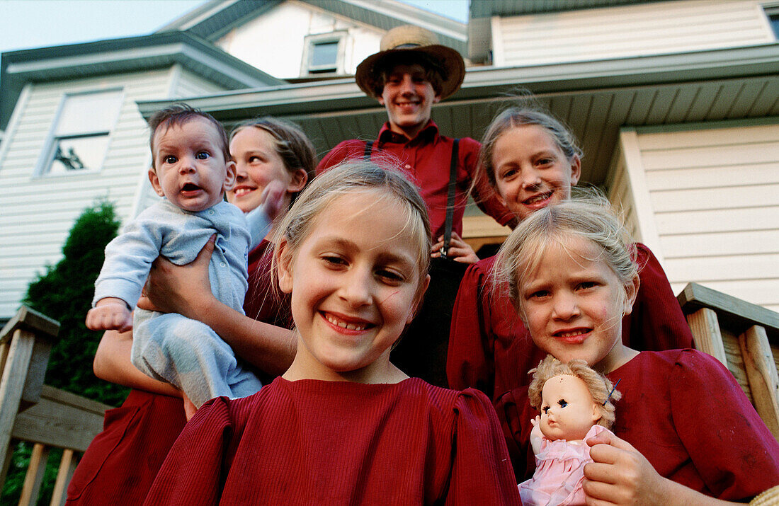Six Amish family children posing at their house entrance. Pennsylvania, USA