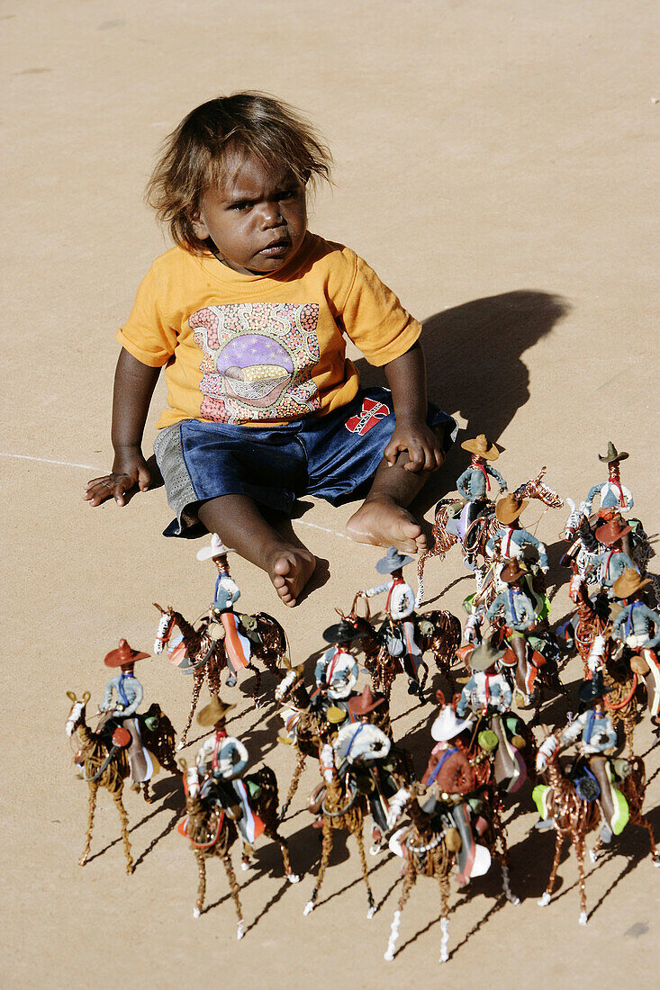 Child playing with small riders sculptures. Gunya Titjikala aborigine community. Northern Territory. Australia